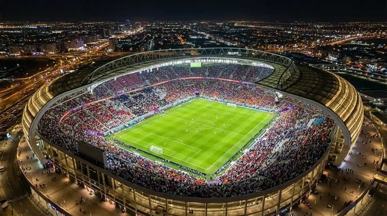Un stade de Coupe du Monde vu de haut la nuit, pelouse éclairée et tribunes pleines, atmosphère de grand rendez-vous